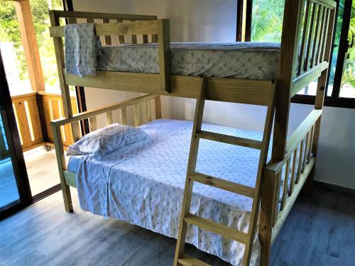 a bunk bed with a ladder next to a small bed at Villa Mi Patio By Hospedify - Hermosa villa con mesa de billar y río cristalino a 3 min Un pequeño paraíso en Jarabacoa in Jarabacoa