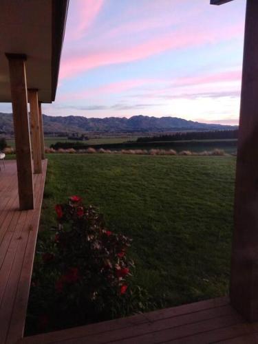 a porch with a view of a green field with flowers at The Bunkhouse in Waiau