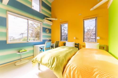 - une chambre avec des murs jaunes et verts et un lit dans l'établissement ビタミンハウス伊豆高原 - vitaminhouse IZUKOGEN, à Itō