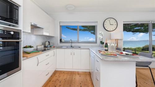 a kitchen with white cabinets and a clock on the wall at Absolute Beach in Callala Beach