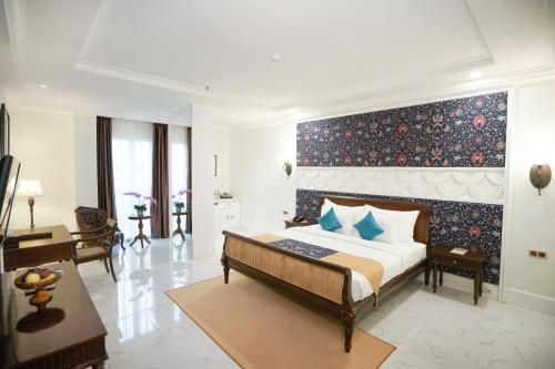 a bedroom with a large bed with a blue wall at MAHALAYA The Legacy Hotel in Solo
