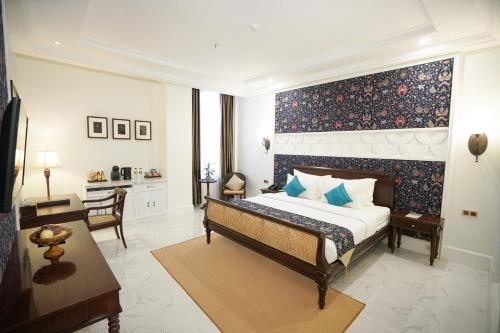 a bedroom with a king sized bed and a desk at MAHALAYA The Legacy Hotel in Solo