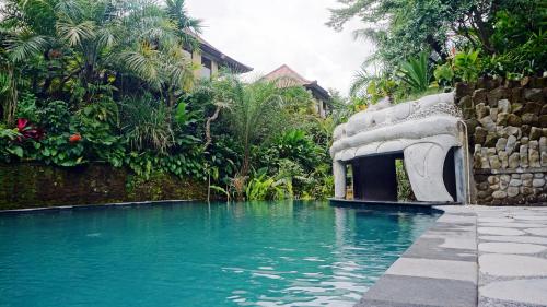 a swimming pool with a building next to a garden at Sakti Garden Resort & Spa in Ubud