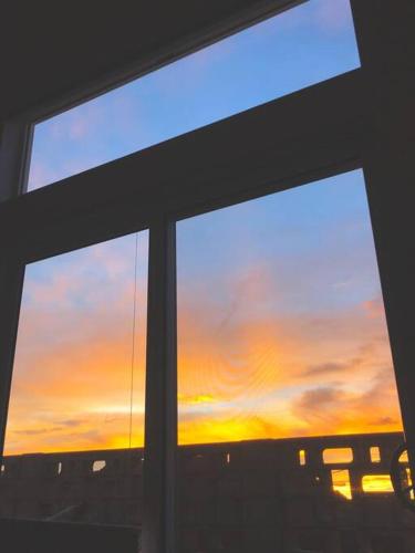 a view of a sunset from a window of a building at Whistling Cloud/ Design+Desert Views+National Park in Joshua Tree
