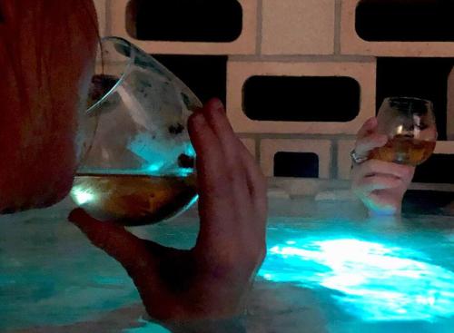 a person holding a glass of wine in a swimming pool at Whistling Cloud/ Design+Desert Views+National Park in Joshua Tree