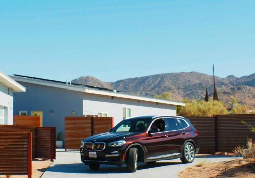 a black car parked in front of a house at Whistling Cloud/ Design+Desert Views+National Park in Joshua Tree