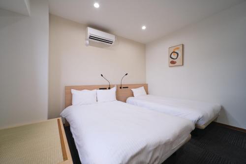 two beds in a room with white sheets at Ano Hotel Asakusa in Tokyo