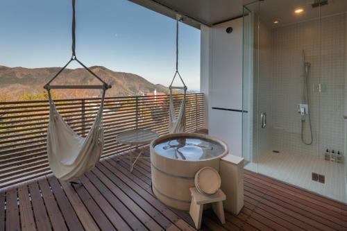 a bathroom with a tub and a hammock on a deck at Hakone Honbako 箱根本箱 in Hakone