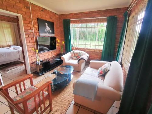 a living room with two couches and a tv at Stone Circle Cottage in Lydenburg