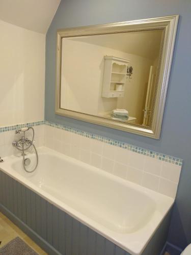 een badkamer met een bad en een spiegel bij Au Cœur de Ménestérol Chambre Émotion in Montpon-Ménestérol