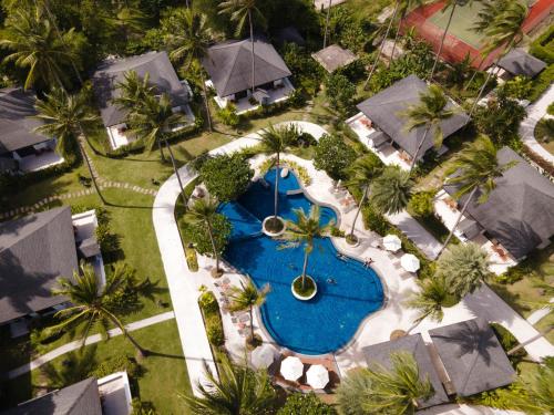 a green lawn with a pool of water and palm trees at The Racha - SHA Extra Plus in Ko Racha Yai