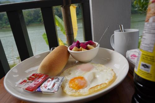 une assiette de nourriture avec un œuf et un bol de fruits dans l'établissement Nam ou view villa, à Nongkhiaw