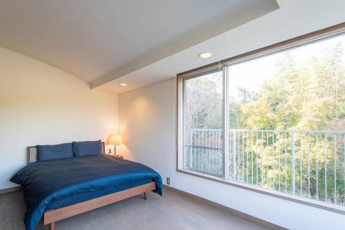 um quarto com uma cama e uma grande janela em Shiki&Kura em Kurashiki