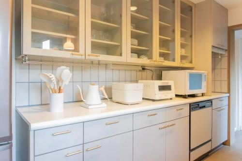 a kitchen with white cabinets and white appliances at Shiki&Kura in Kurashiki
