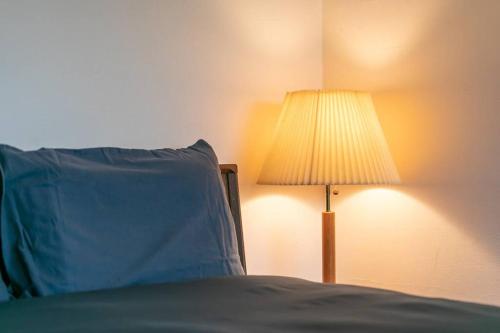 a bed with a blue pillow next to a lamp at Shiki&Kura in Kurashiki