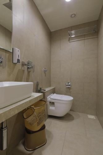 a bathroom with a white sink and a toilet at Hotel Elysian Residency in Ahmedabad
