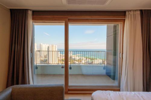 een slaapkamer met een balkon met uitzicht op de oceaan bij Hotel The Blue Terra in Sokcho