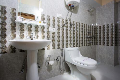 a bathroom with a white toilet and a sink at Golden Oren Hotels and Spa in Darjeeling