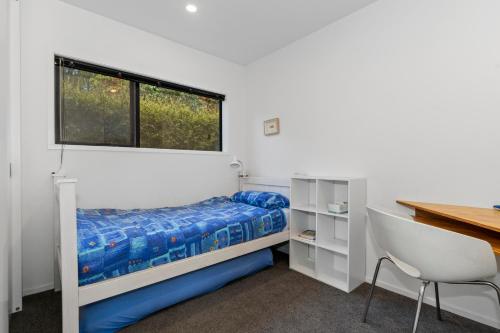 um quarto com uma cama, uma secretária e uma janela em Tapuaetahi Beach Marvel - Te Tii Holiday Home em Waipapa