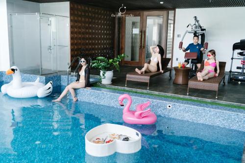 a group of people sitting around a swimming pool at Nostalgia Boutique Hotel in Da Nang