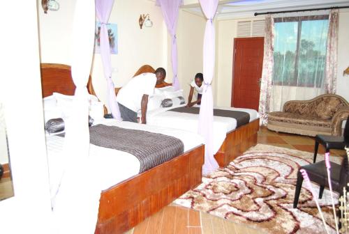 two people standing in a bedroom with two beds at Aturukan Hotel in Kitale