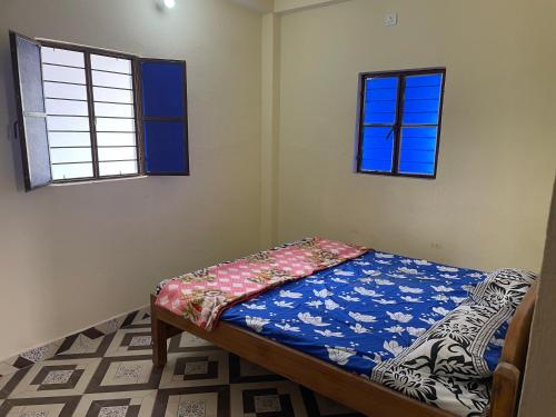 a bedroom with a bed and two windows at Shubham guest house in Muzaffarpur