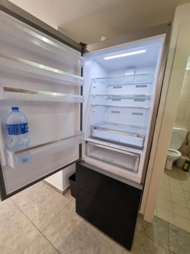 an empty refrigerator with a bottle of water in it at Sunset and sea view, wifi and more in Ashqelon