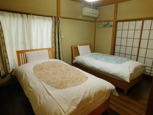 那須町にある貸別荘「ブライト那須」のベッド2台と窓が備わる客室です。