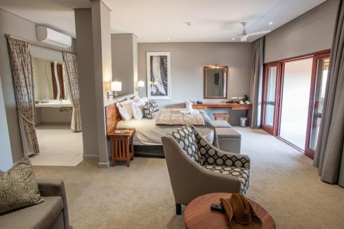 Habitación de hotel con cama y sala de estar. en Chobe Safari Lodges en Kasane