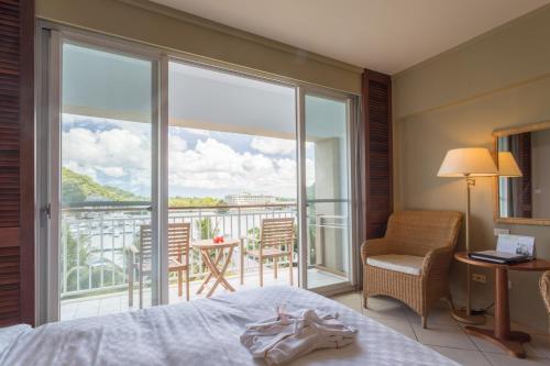 a bedroom with a bed and a view of a balcony at Palau Royal Resort in Koror