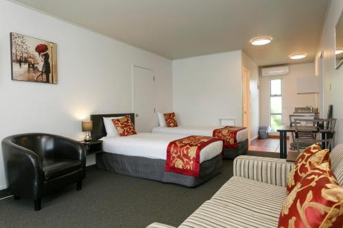 Habitación de hotel con cama y silla en Great Lake Motel Taupo en Taupo