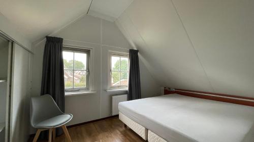 een slaapkamer met een bed en een stoel op zolder bij Buitenhuis de Bosuil in Hoge-Hexel
