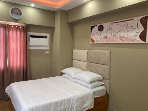 um quarto com uma cama com lençóis brancos e almofadas em 1523 MIGAs Haven at Sunvida across SM City em Cebu