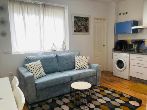 Il comprend un salon avec un canapé bleu et une cuisine. dans l'établissement Apartamentos Bahía, à El Puerto de Santa María