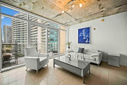 a living room with a couch and a table and windows at Amazing 2 Bed in Midtown with FREE Parking in Miami