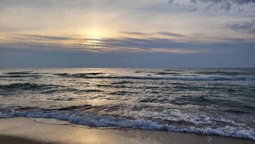 a beach with the ocean with the sun setting on the horizon at Amber Family Home Juodkrantė in Juodkrantė