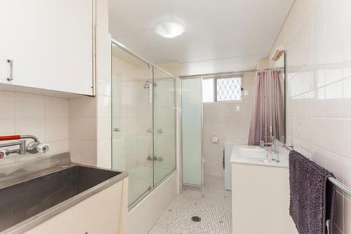 ein weißes Bad mit einer Dusche und einem Waschbecken in der Unterkunft Goodwin Towers - Hosted by Burleigh Letting in Gold Coast