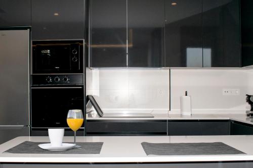 a black kitchen with a glass of wine on a counter at Deluxe Apartament Alcalá la Real in Alcalá la Real