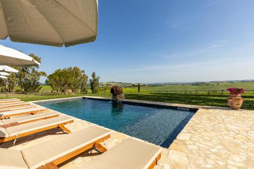 a swimming pool with chairs and an umbrella at Wine Resort Colsereno in Montalcino