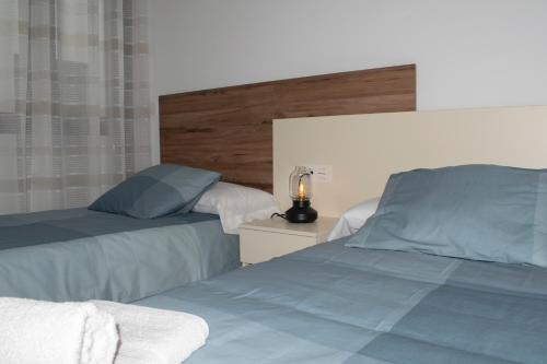 1 dormitorio con 2 camas y mesita de noche con lámpara en Deluxe Apartament Alcalá la Real, en Alcalá la Real