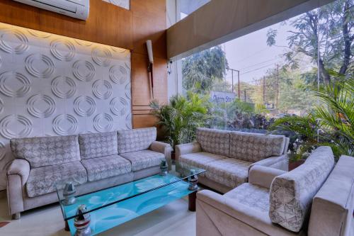 a living room with two couches and a glass table at Hotel Amrit Residency in Indore