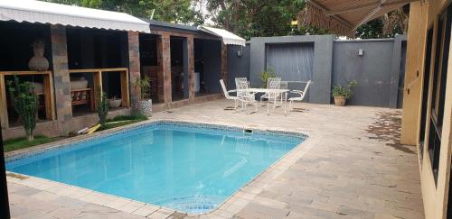 una piscina con mesa y sillas junto a una casa en Upland Estates Serviced Apartments, en Lusaka