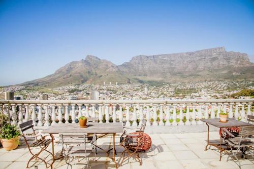 a balcony with tables and chairs with mountains in the background at Dorp Hotel in Cape Town