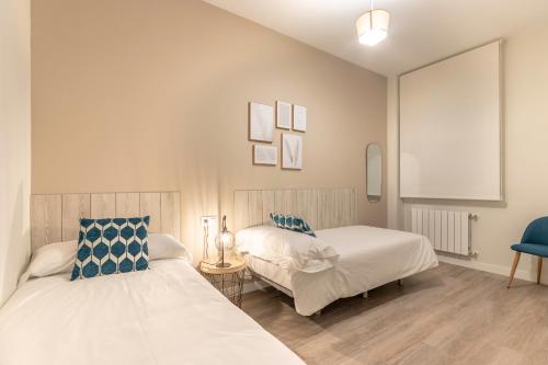 1 dormitorio con 2 camas y silla azul en Recién reformado junto a metro San Mamés, en Bilbao