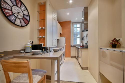 une cuisine avec une table et une horloge au mur dans l'établissement LA BALANCE DES DOMS - 1 MIN du PALAIS des PAPES - INTRA-MUROS, à Avignon