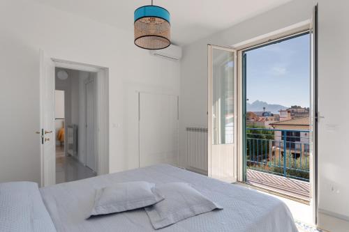 a white bedroom with a bed and a large window at Solemar Sicilia - Casa Margherita in Santa Flavia