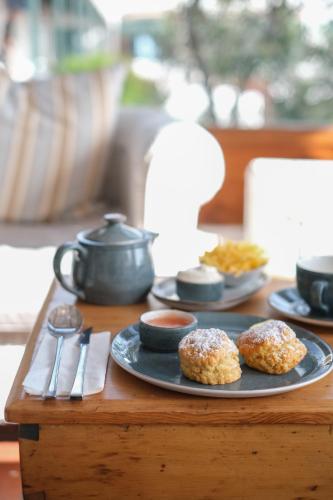 two donuts on a plate on a wooden table at Adventure Pad's by The Farmhouse Hotel in Langebaan