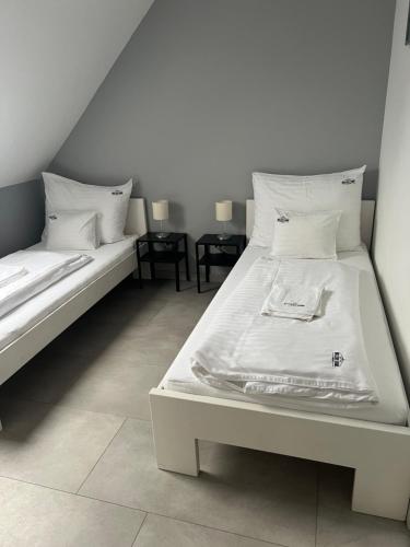 um quarto com 2 camas com lençóis brancos e almofadas em MISLENY HOME em Kozármisleny