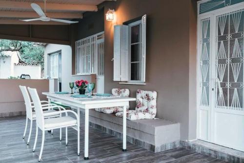 a white table and chairs on a porch with a window at The Mills House in Kallithea