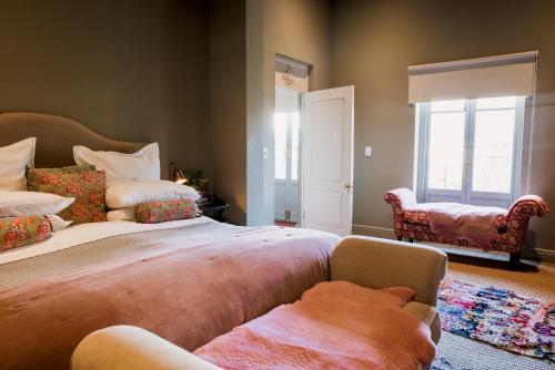 a bedroom with two beds and a chair and windows at Dorp Hotel in Cape Town
